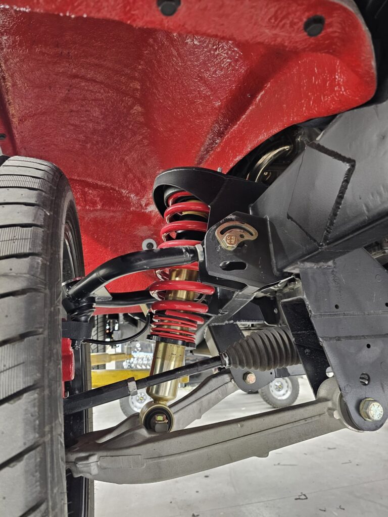 Frame-Werx front suspension and coilover in the red wheel well of the 85 Chevy extended cab