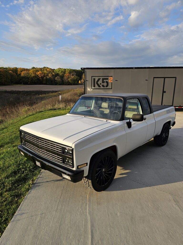 White 85 Chevy extended cab beside the K5 Squared trailer