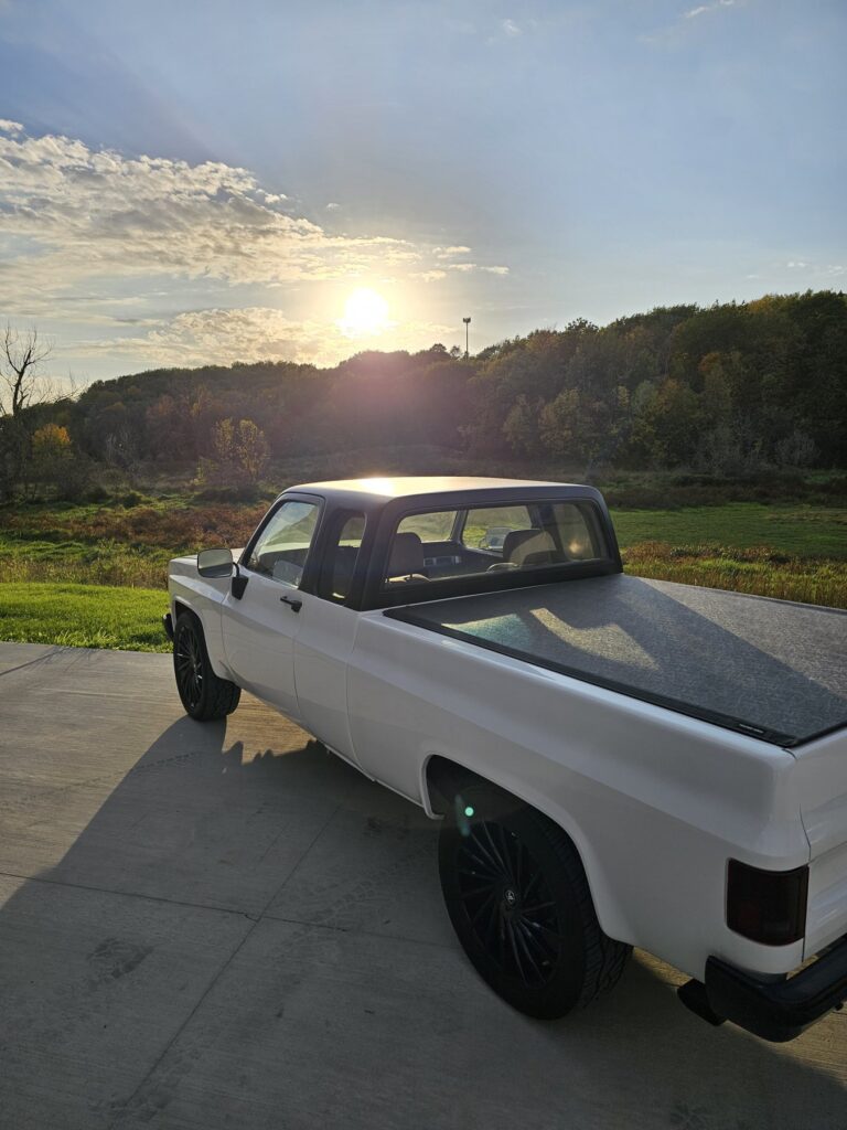 White 85 Chevy extended cab at sunset, rear three-quarter